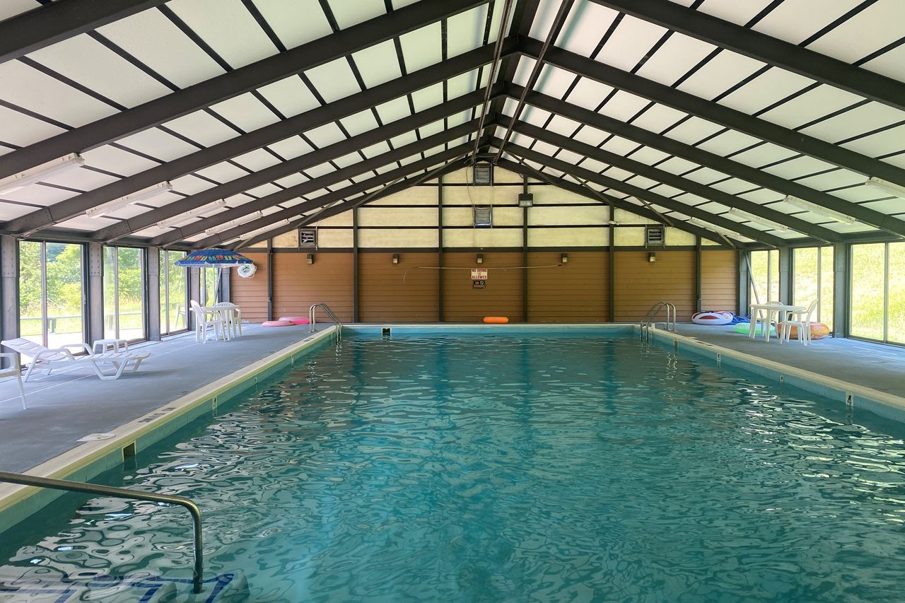 A large indoor swimming pool with a covered roof and a lot of windows.