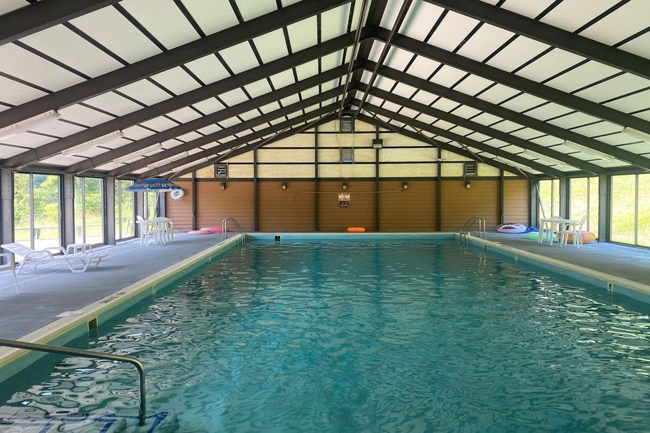 A large indoor swimming pool with a covered roof and a lot of windows.