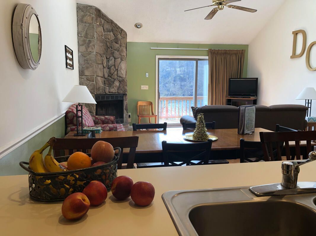 A bowl of fruit sits on a counter next to a sink in a living room.