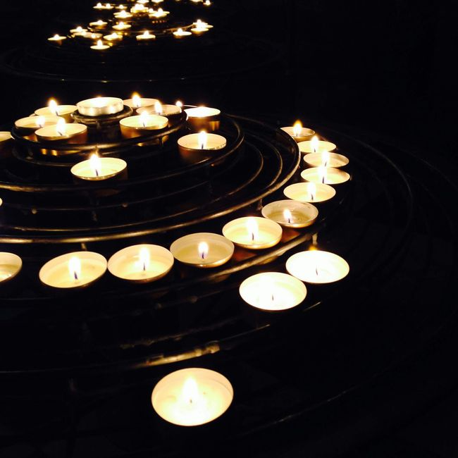 Burning candles in a spiral arrangement, creating a warm glow in the dark.