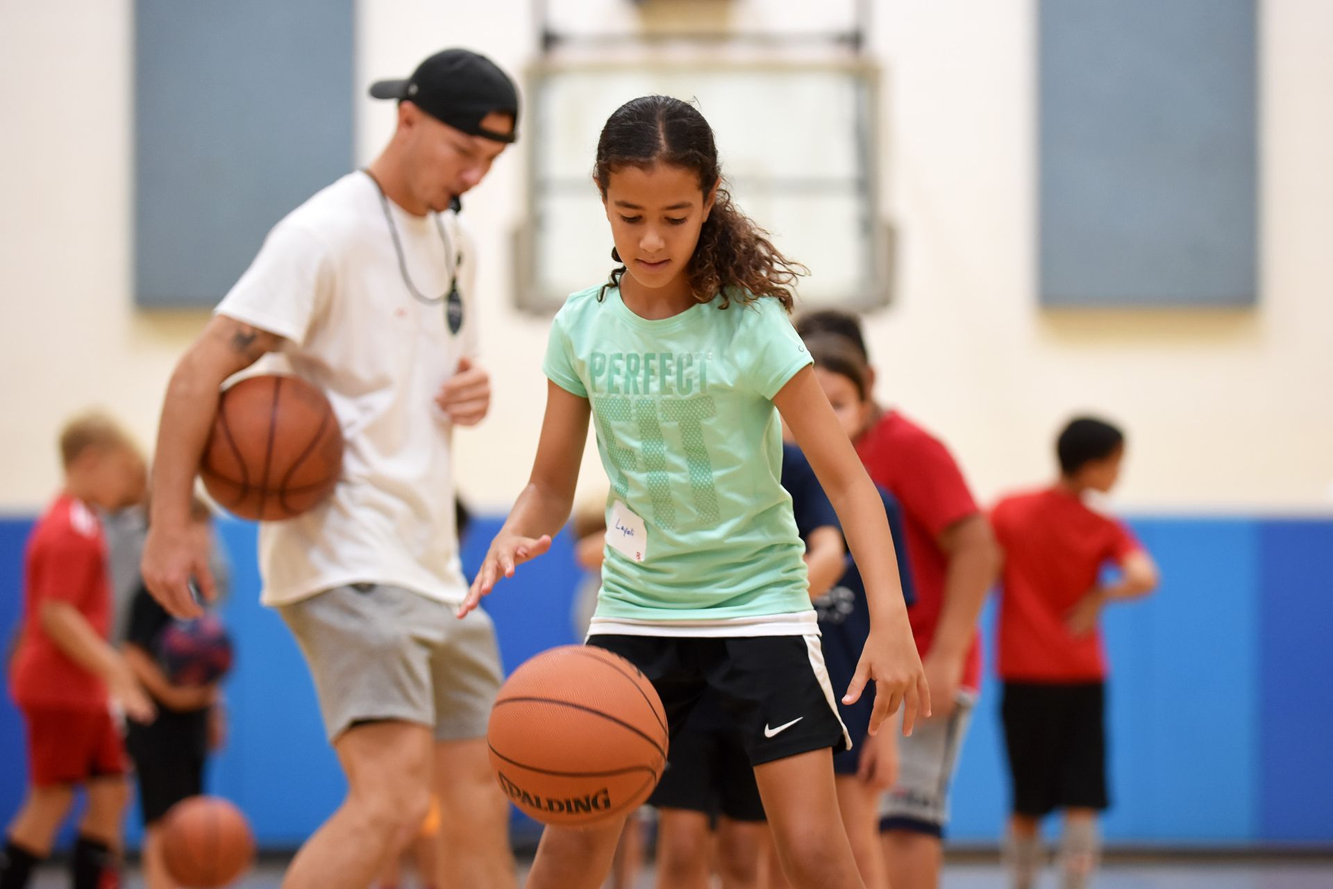 People dribbling basketballs during an indoor practice session