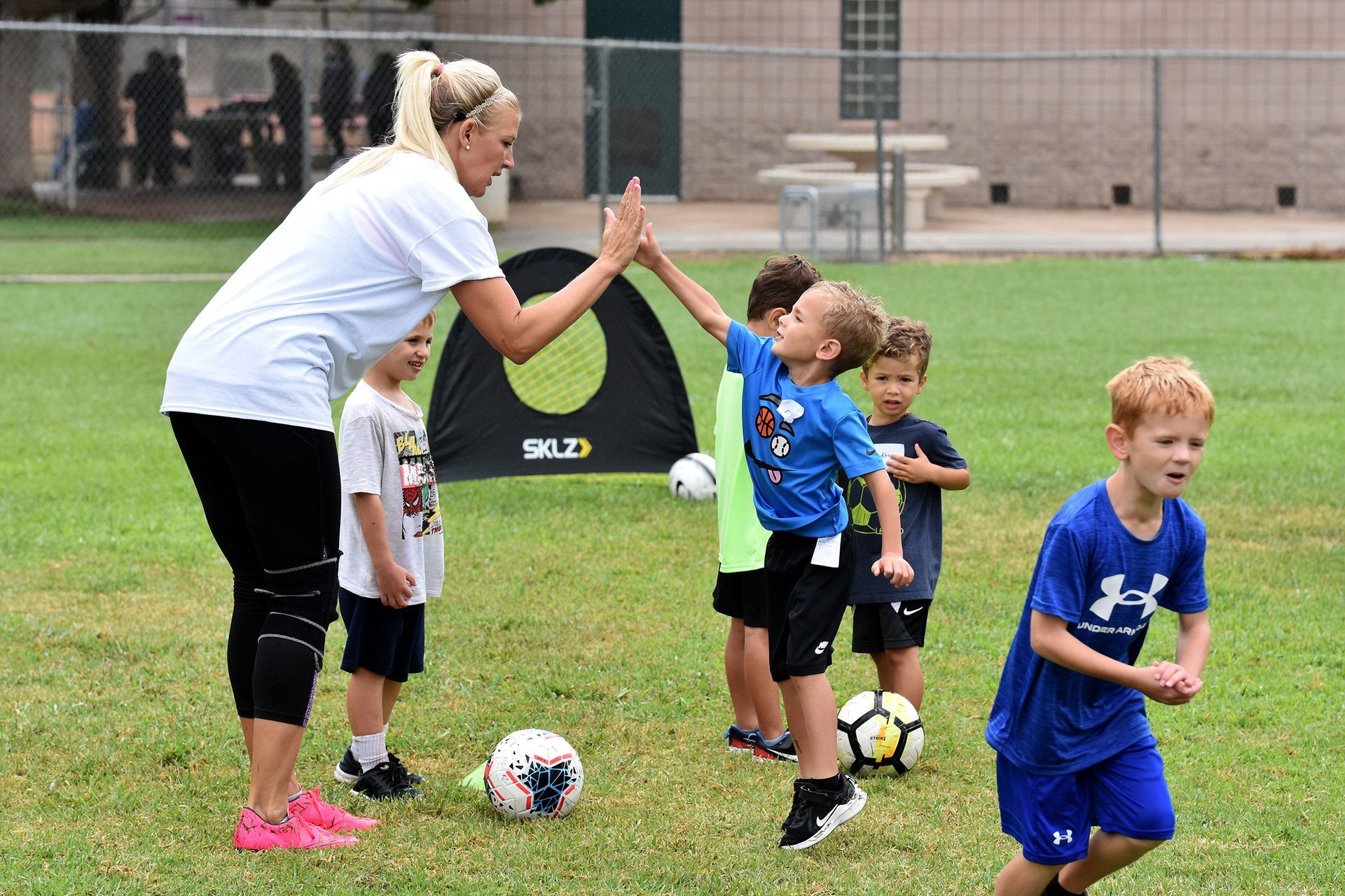 Soccer coach giving a high-five to children during practice on a grassy field