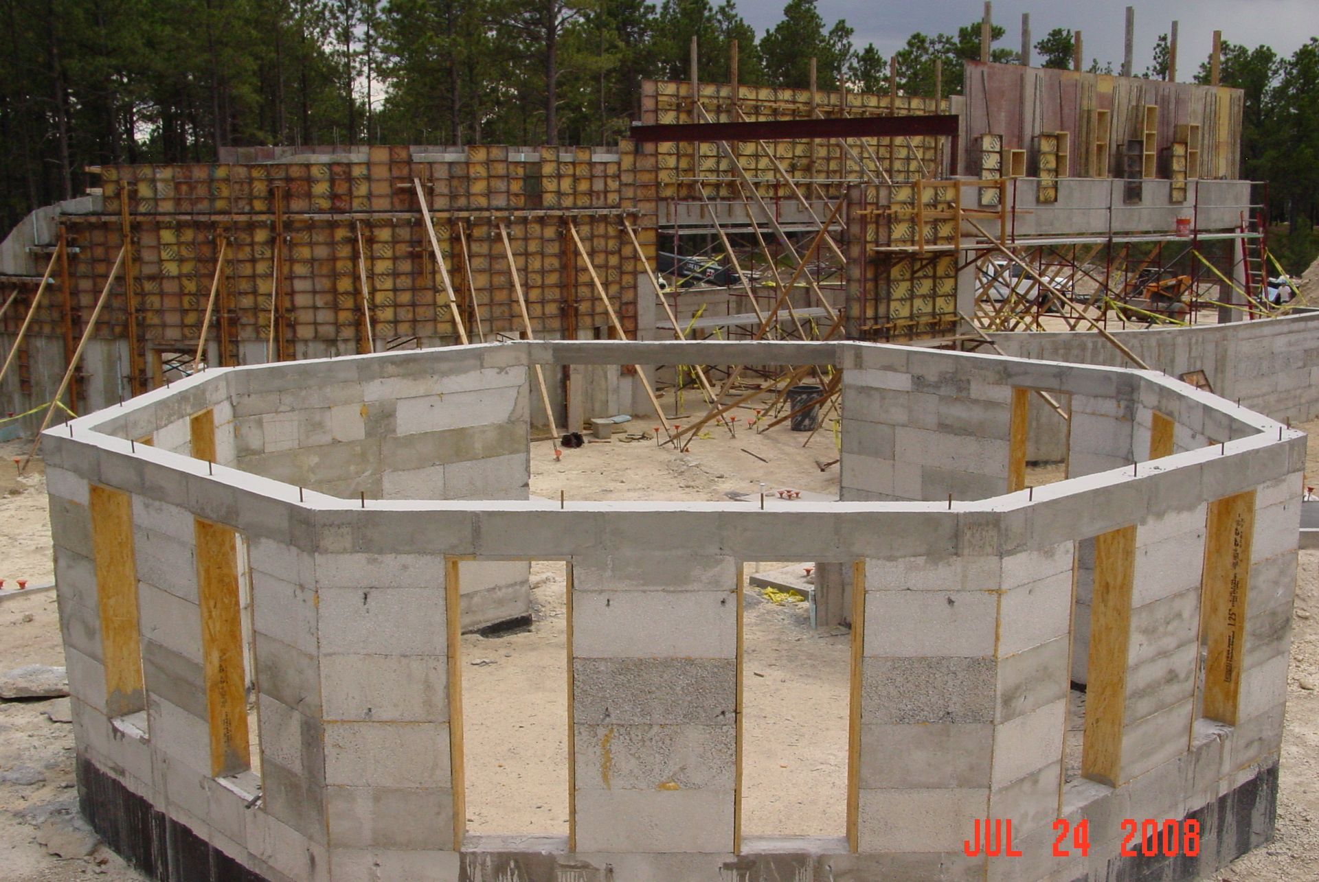 Construction site with workers and a concrete pump, building a concrete structure.
