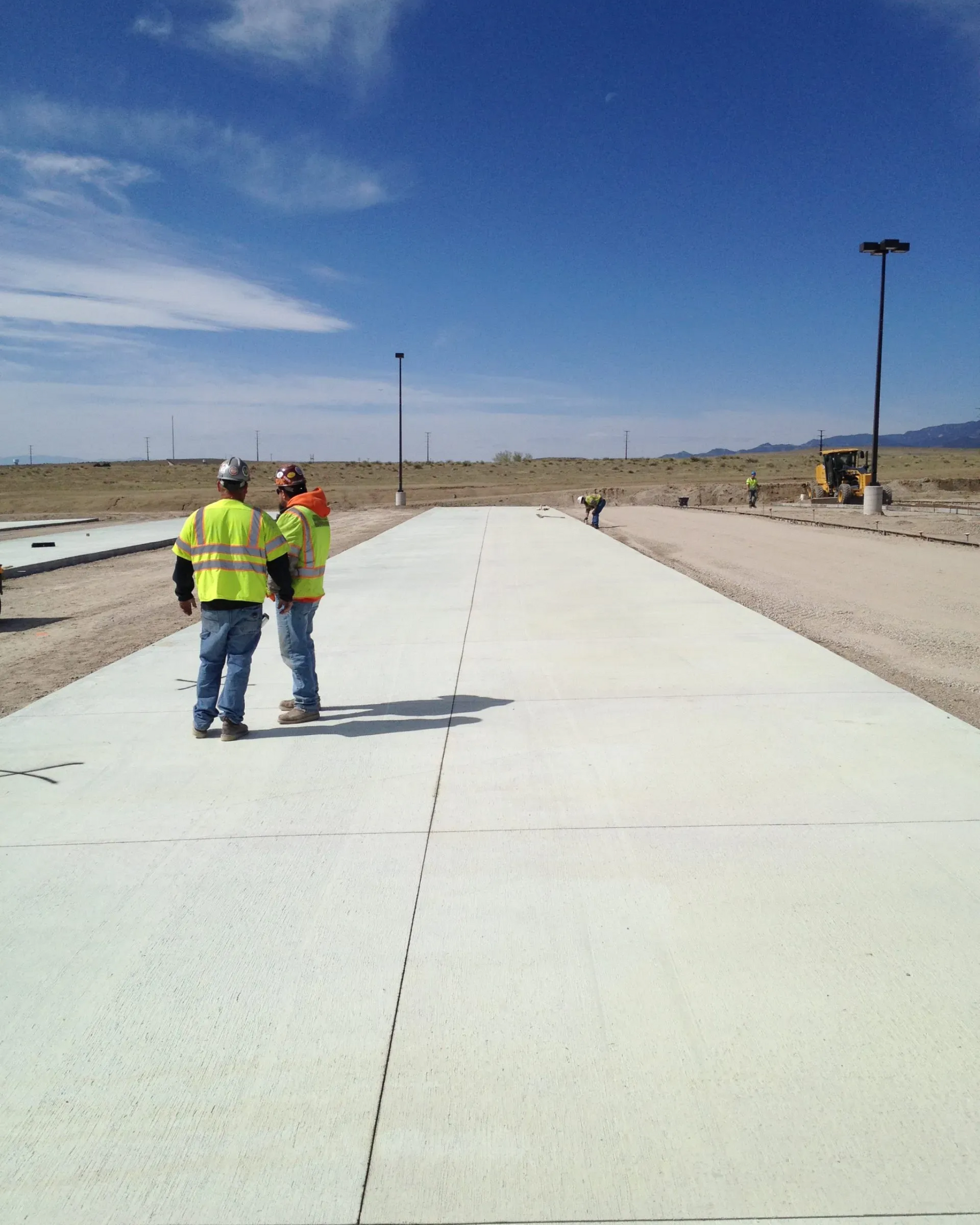 A concrete pump is being used to pour concrete on a construction site with mountains in the background.