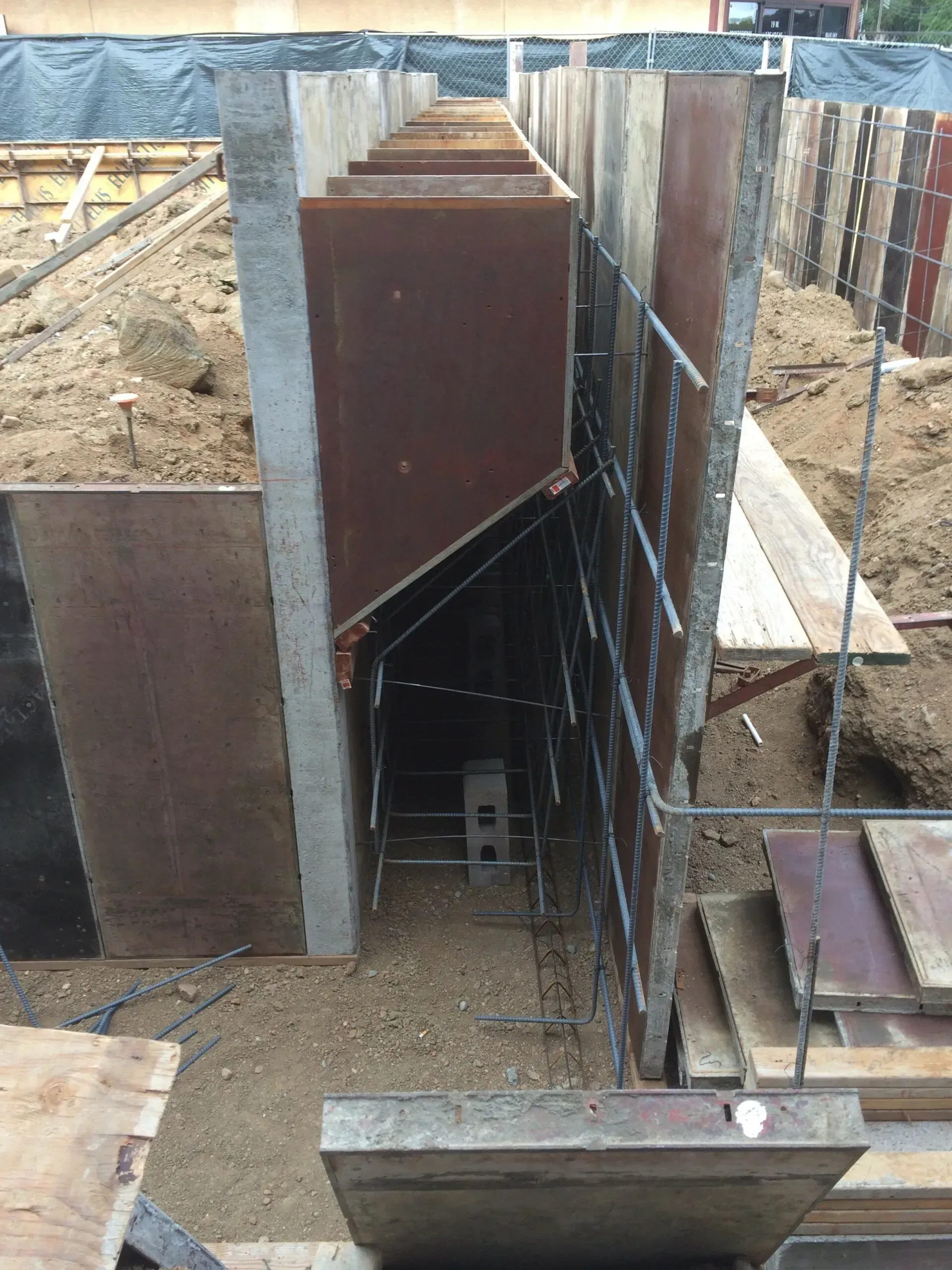 Reinforced concrete wall under construction with exposed rebar.