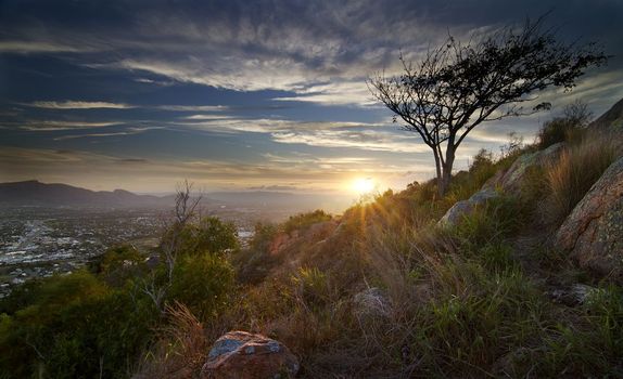 The Sun Is Setting Behind A Tree On Top Of A Hill — Custom Steel Fab in Townsville, QLD