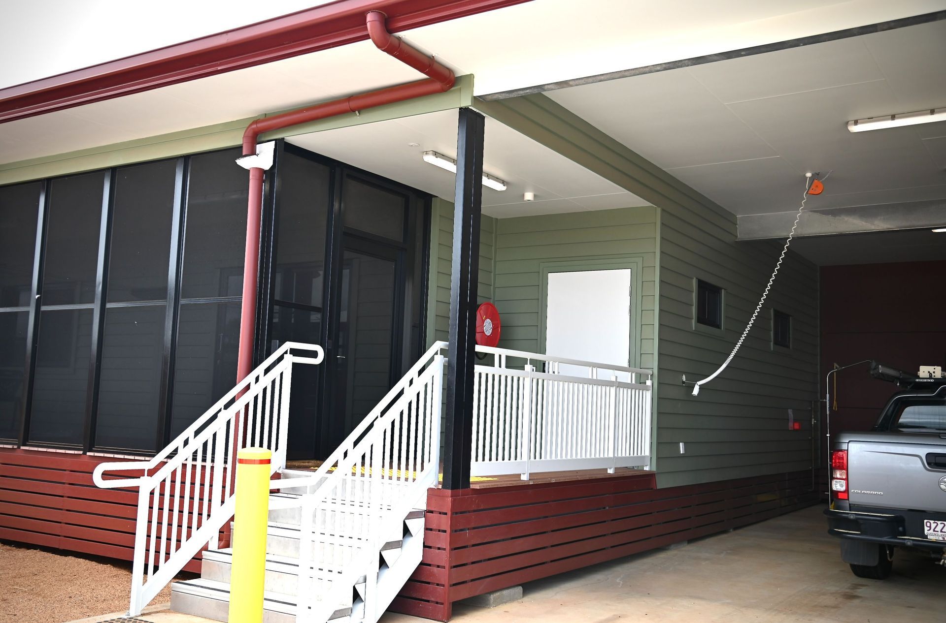 A truck is parked in front of a building with stairs leading up to it.