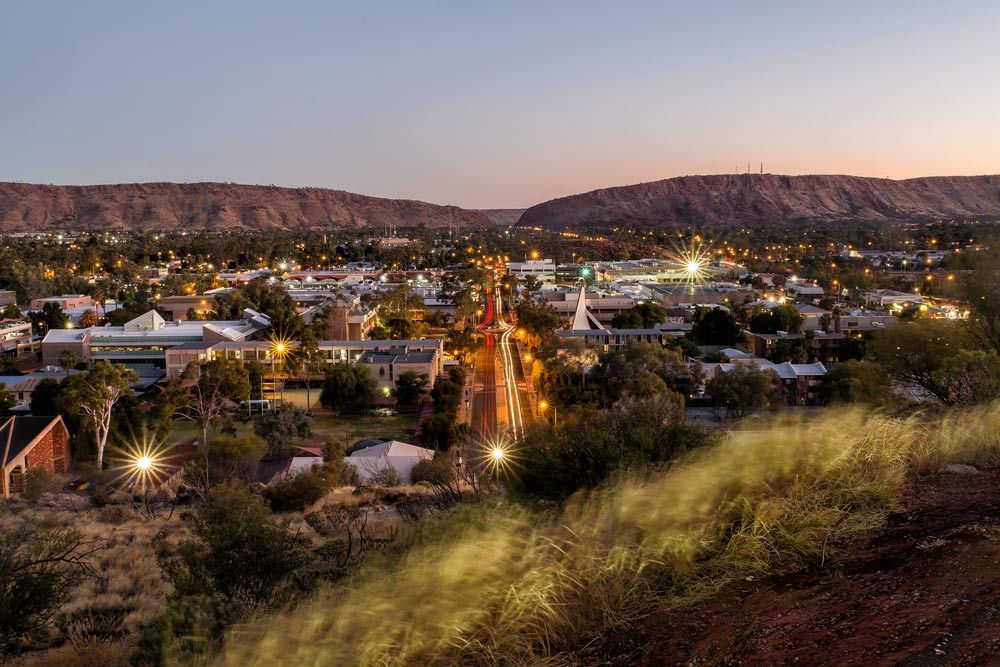 An Aerial View Of A City At Night With Mountains In The Background — Custom Steel Fab in Alice Springs, NT