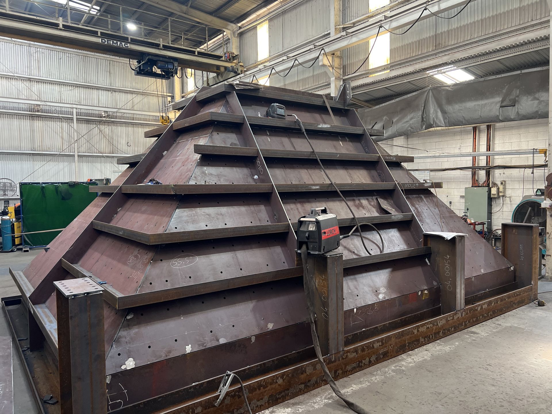 A large metal structure is being built in a factory.