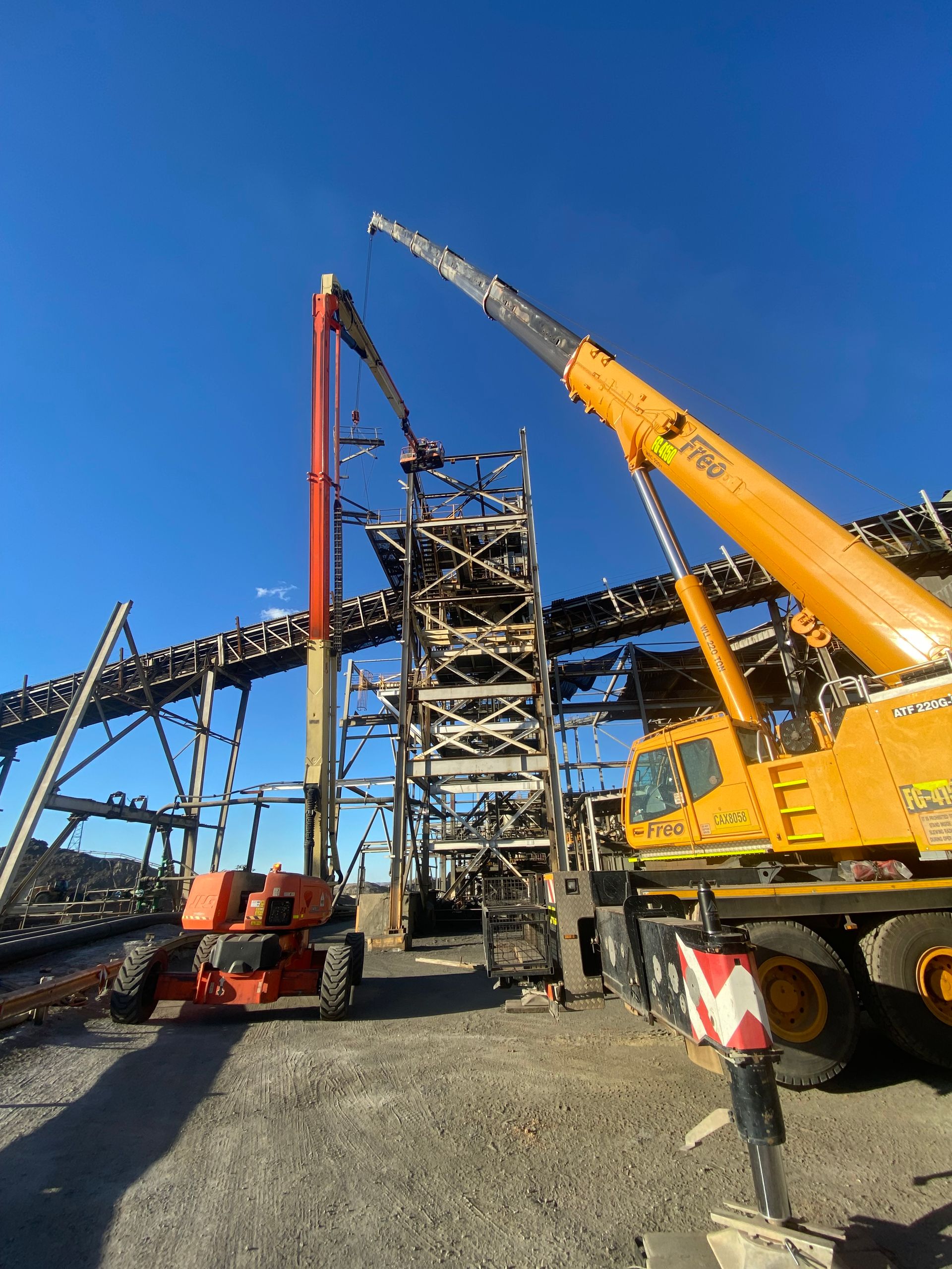 A Large Yellow Crane Is Sitting In Front Of A Building Under Construction — Custom Steel Fab in Mount Isa, QLD