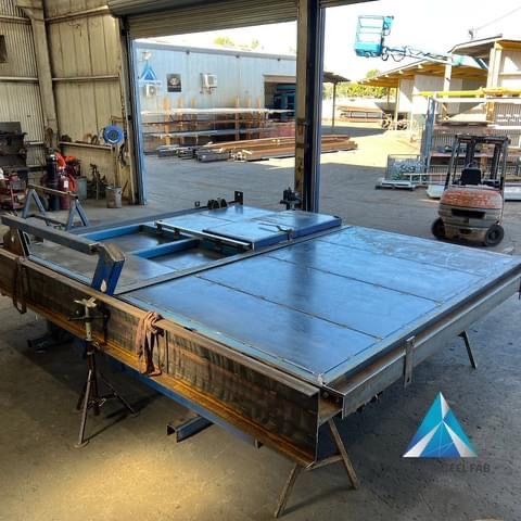 A Large Piece Of Metal Is Sitting In A Garage Next To A Forklift — Custom Steel Fab in Garbutt, QLD