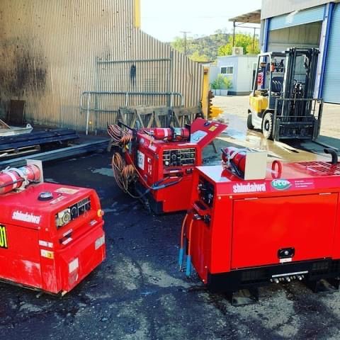 Two red machinery are parked next to each other in a parking lot.