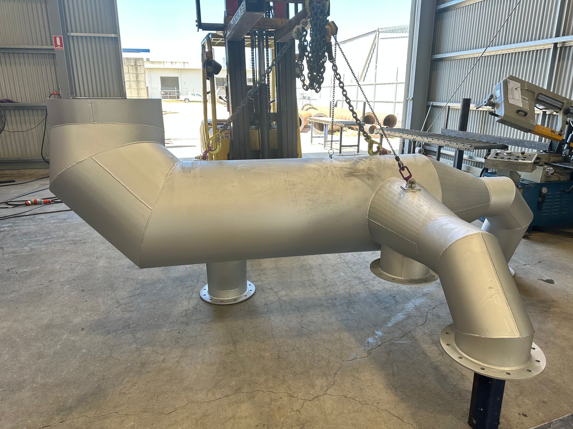 A large metal pipe is sitting on the floor in a warehouse.