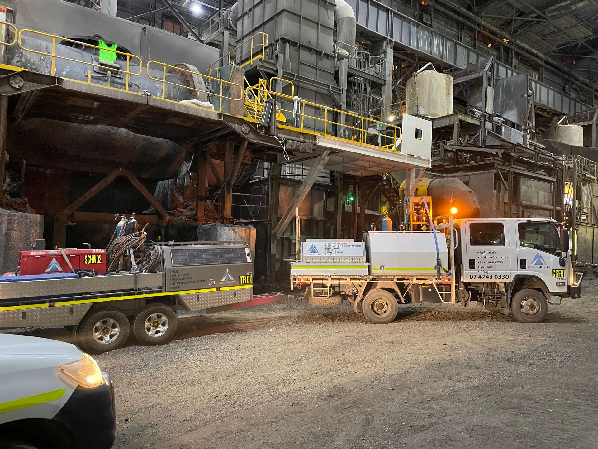 Two Trucks Are Parked In Front Of A Large Building — Custom Steel Fab in Townsville, QLD