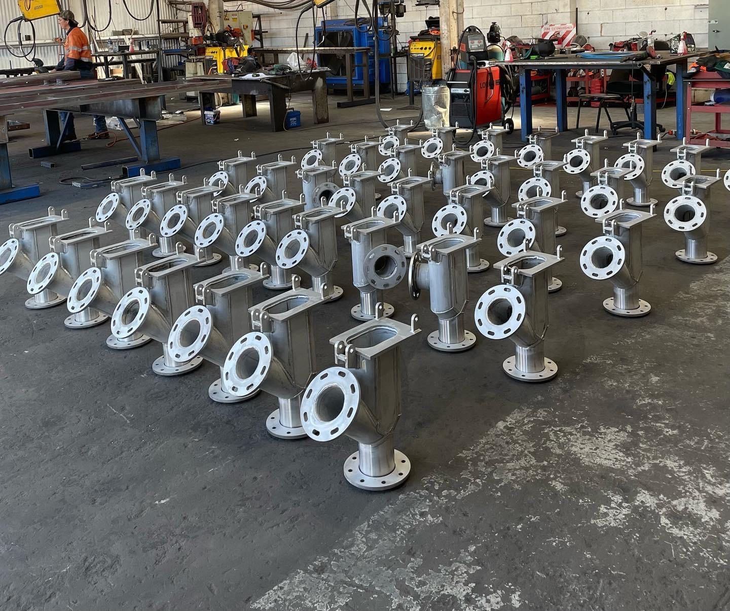 A bunch of metal pipes are lined up in a factory