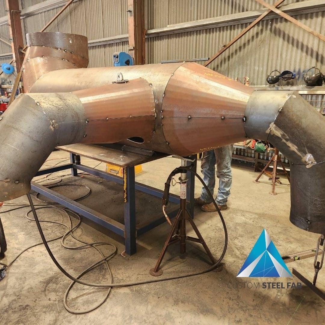 A Large Piece Of Metal Is Sitting On A Table In A Warehouse — Custom Steel Fab in Garbutt, QLD