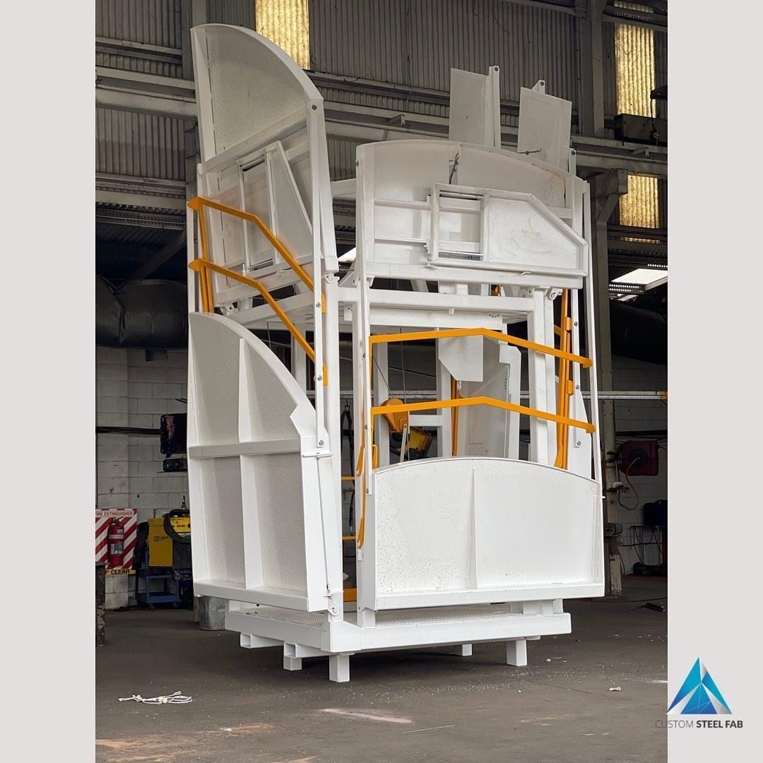 A large white box with a yellow railing in a warehouse