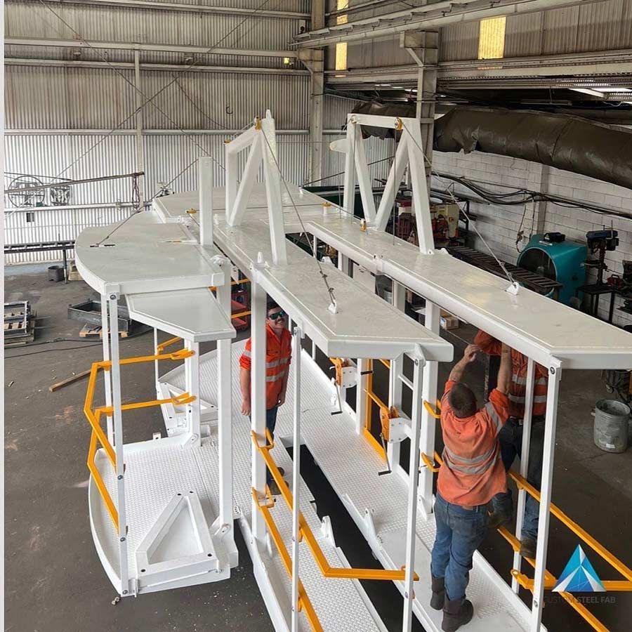 A Man Is Working On A Large White Structure In A Warehouse — Custom Steel Fab in Hughenden, QLD