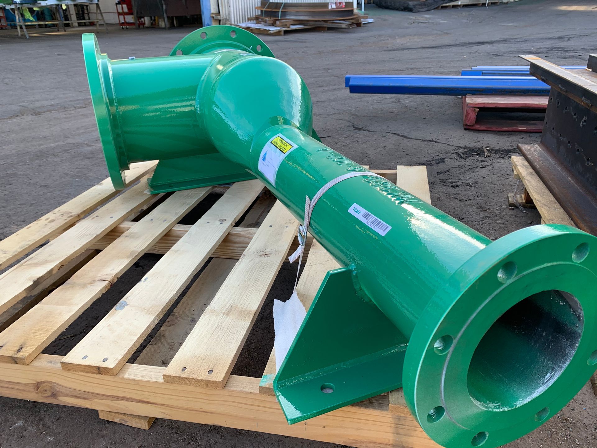 A green pipe is sitting on a wooden pallet