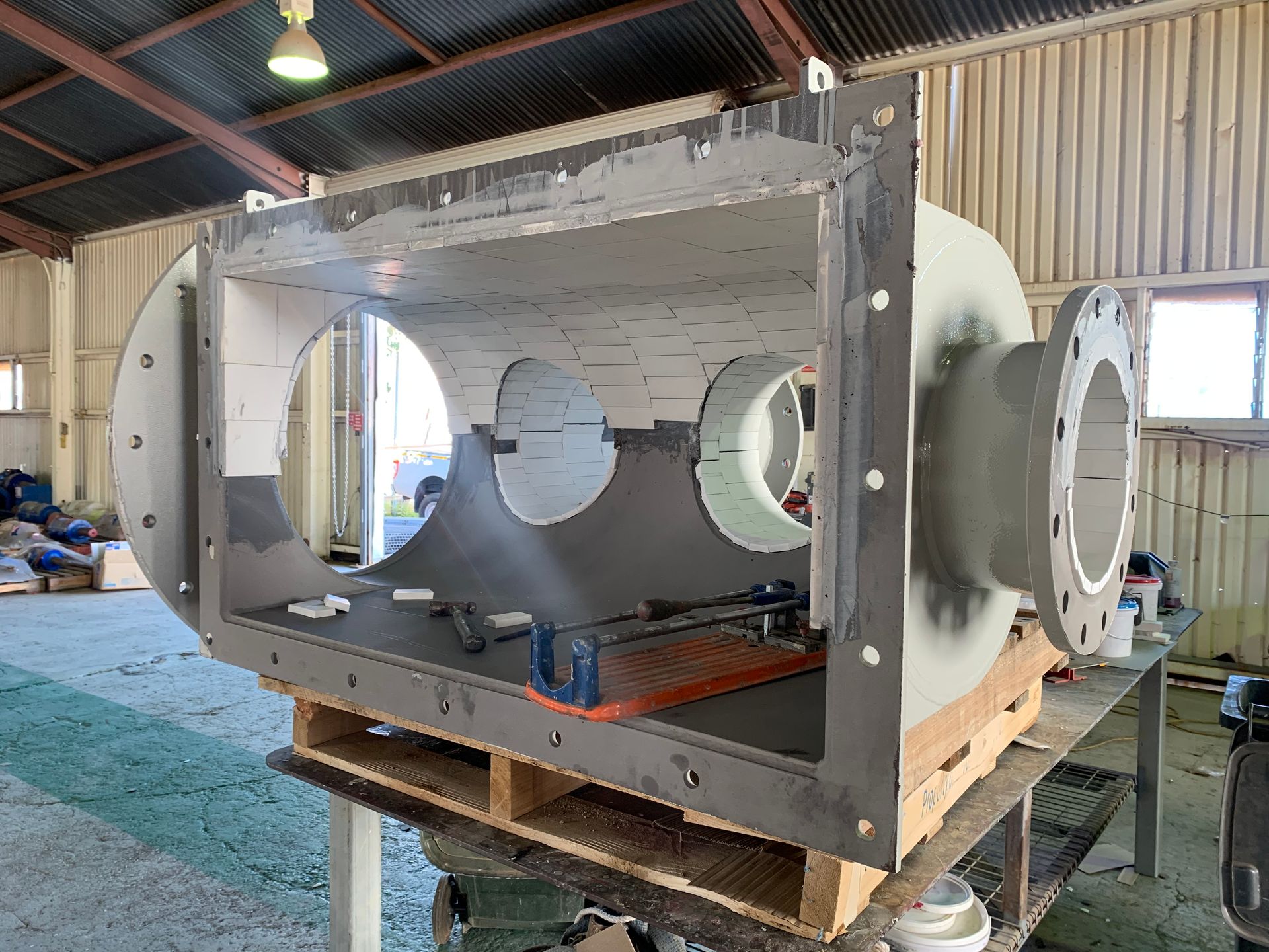 A Large Metal Object Is Sitting On Top Of A Wooden Pallet In A Warehouse — Custom Steel Fab in Garbutt, QLD