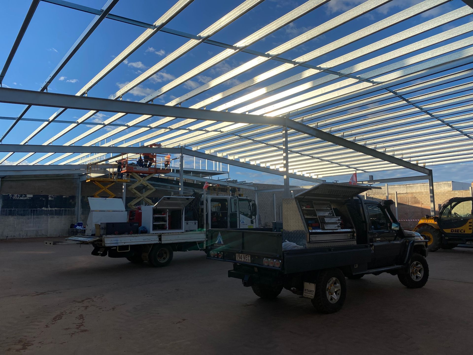 A truck is parked under a clear roof in a parking lot.