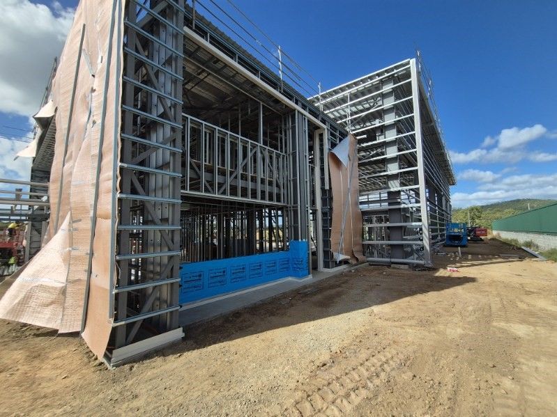 A large building is being built in a dirt field.