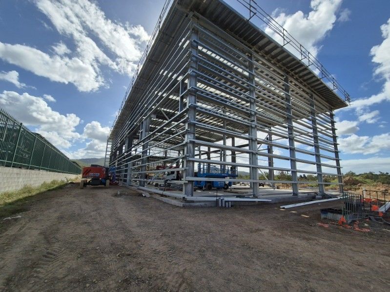 A large metal structure is being built in a dirt field.