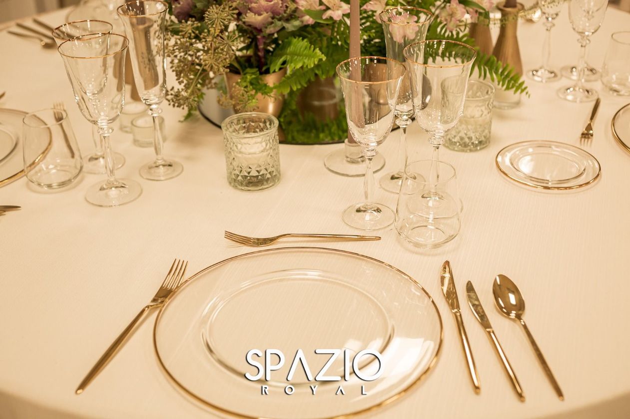 Un tavolo apparecchiato per un ricevimento di nozze con piatti, posate e un vaso di fiori.