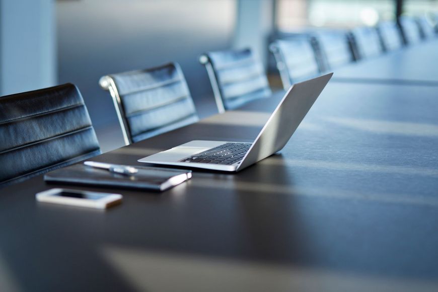 Un computer portatile è appoggiato su un tavolo da conferenza.