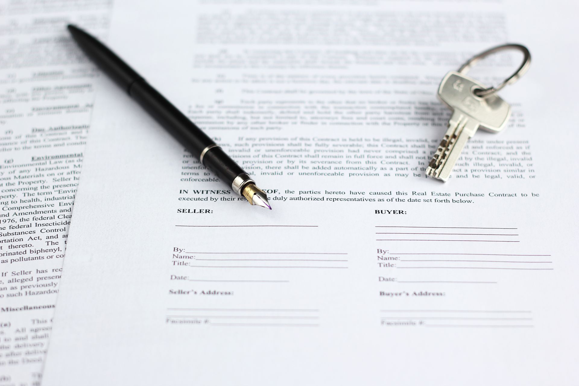 Legal document for sale of real estate, with a gold-nibbed fountain pen and house keys.