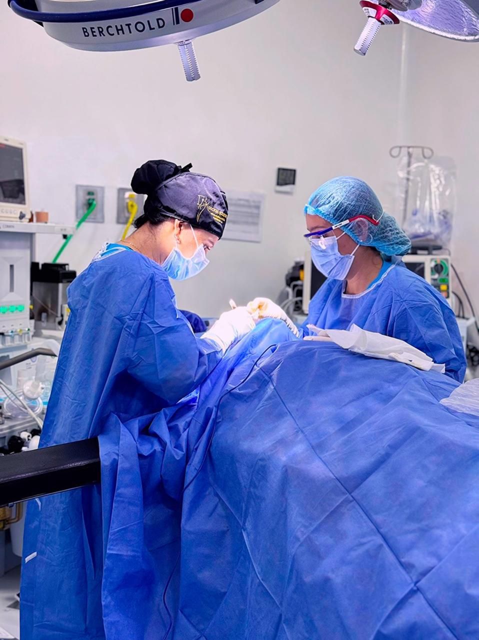 Dos cirujanos están operando a un paciente en un quirófano.