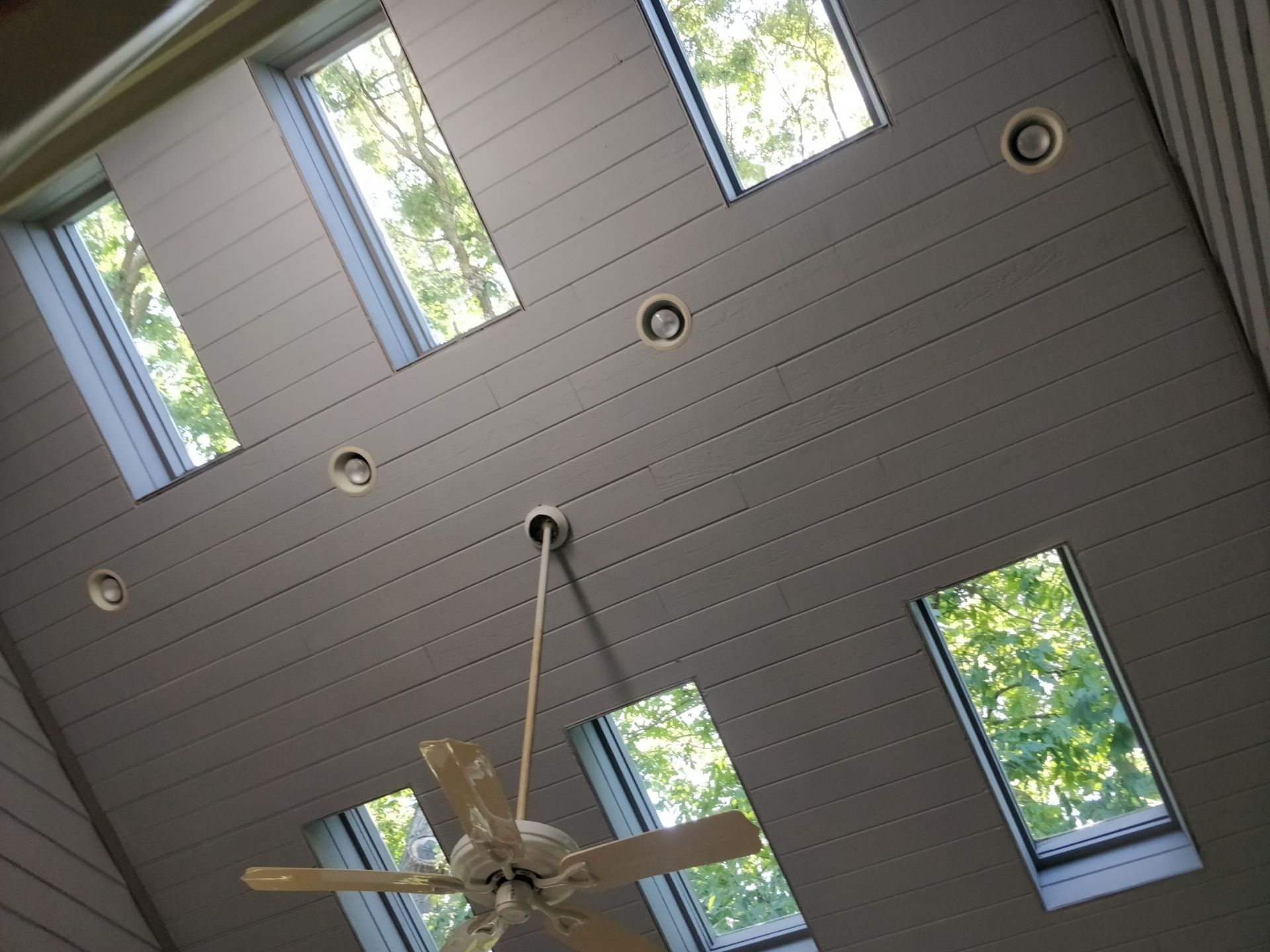 A ceiling fan is hanging from the ceiling in a room with many windows