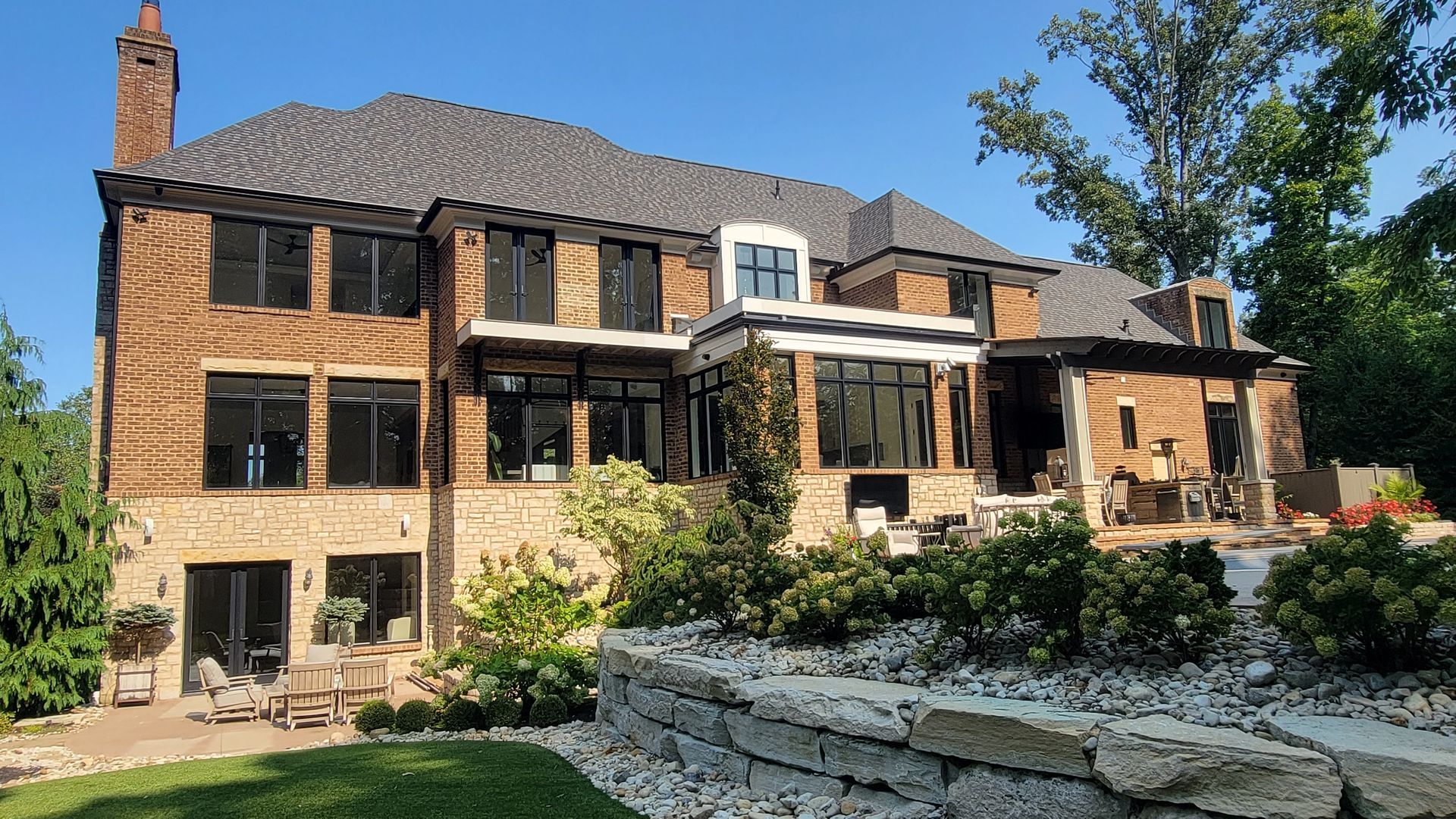A large brick house with a stone wall in front of it
