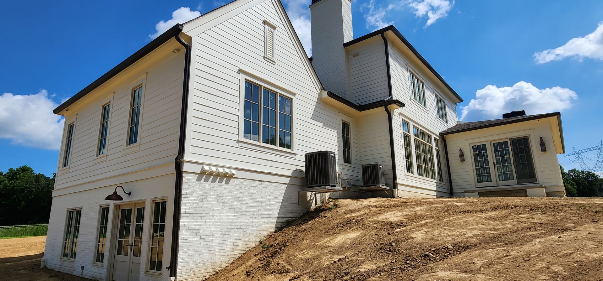 A large white house is sitting on top of a dirt hill.
