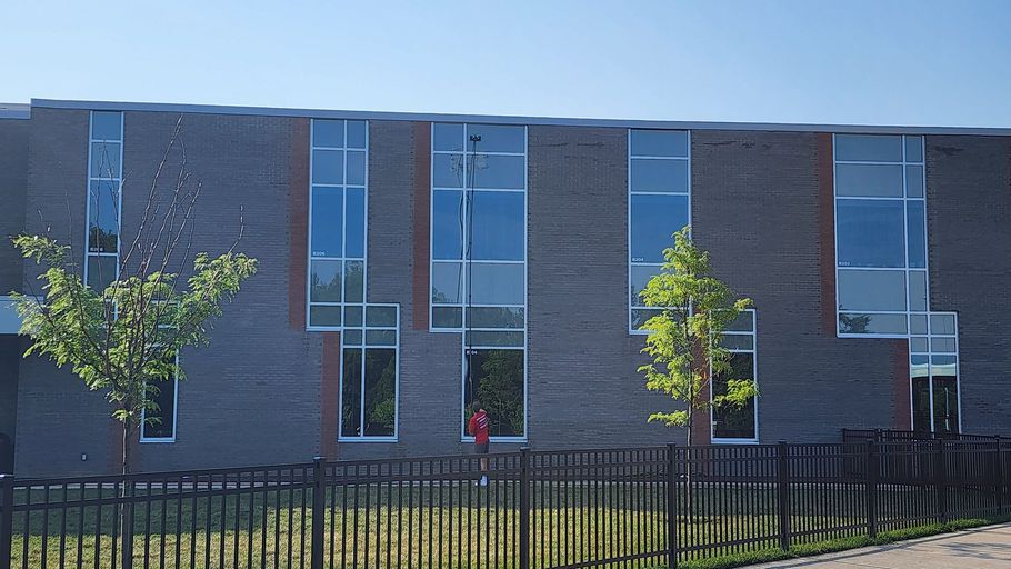 A large brick building with lots of windows is behind a fence.