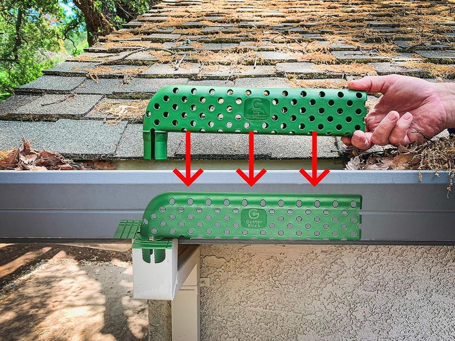 A person is cleaning a gutter with a green tool.