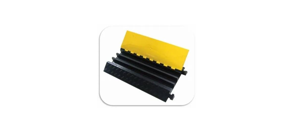A black and yellow rubber cable protector ramp with three channels for shielding cords on the floor.