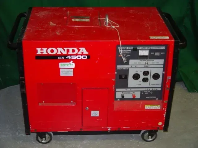A red Honda EX 4500 portable generator with black frame, wheels, and control panel on a light surface.