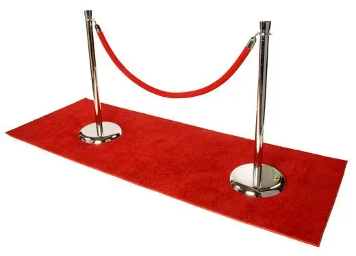 A red carpet runner with two chrome stanchions connected by a red velvet rope.