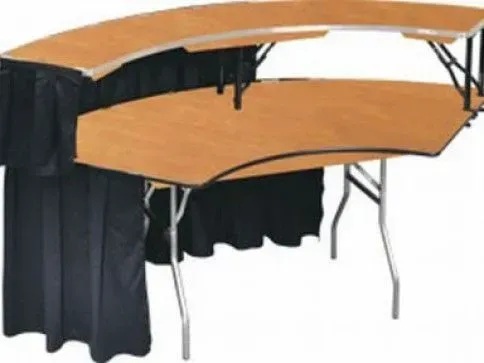 A two-tiered, curved reception desk with a light wood-grain finish and black fabric skirting on metal folding legs.