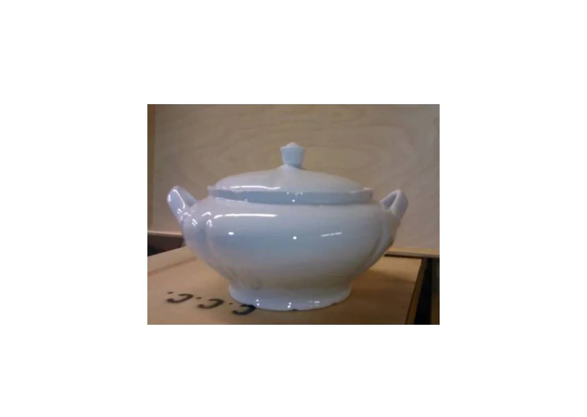 A white, lidded ceramic tureen with two side handles, sitting on a light-colored surface.