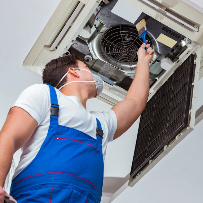 A man wearing a mask is working on an air conditioner