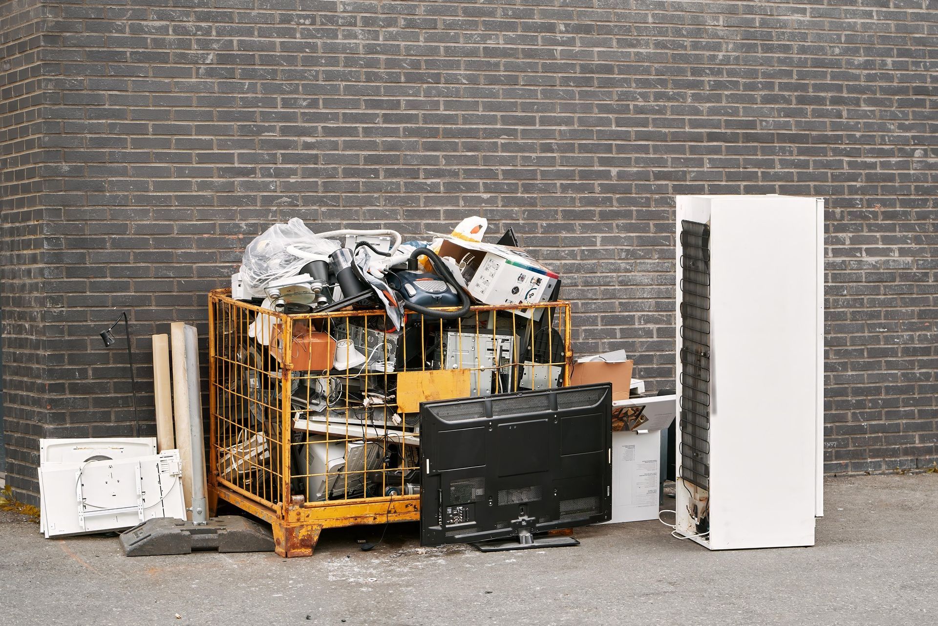 A pile of trash is sitting in front of a brick wall.