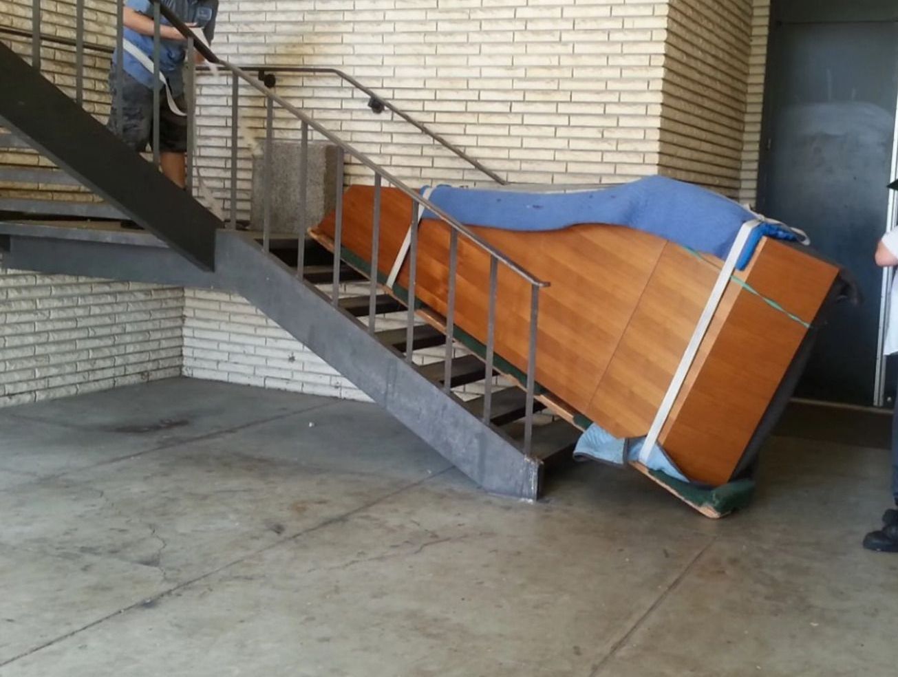 A piano is being moved up a set of stairs