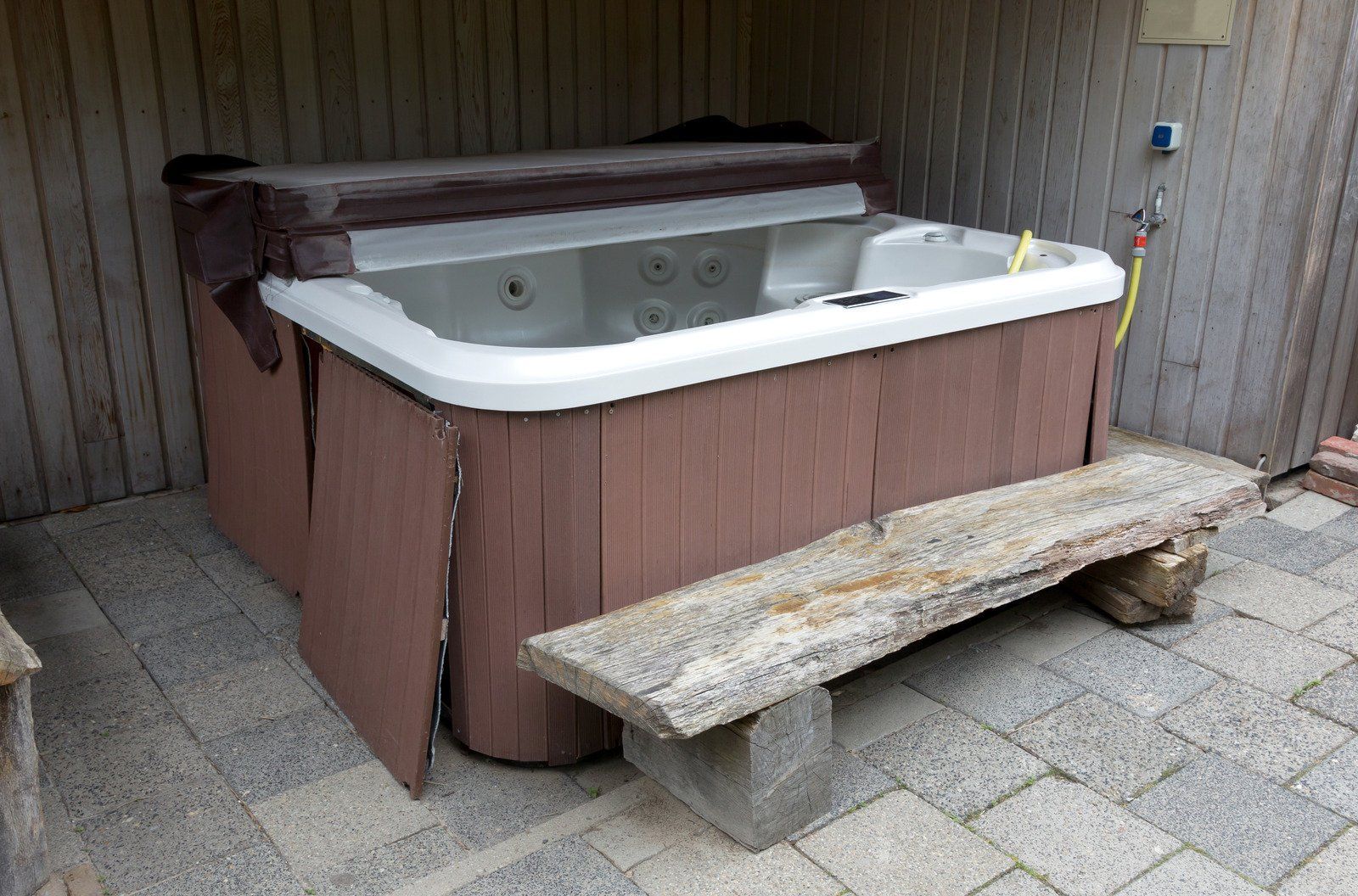 A hot tub is sitting on a patio next to a wooden bench.