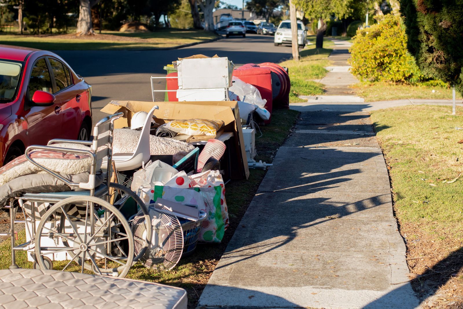 A wheelchair is sitting on the sidewalk next to a pile of trash.