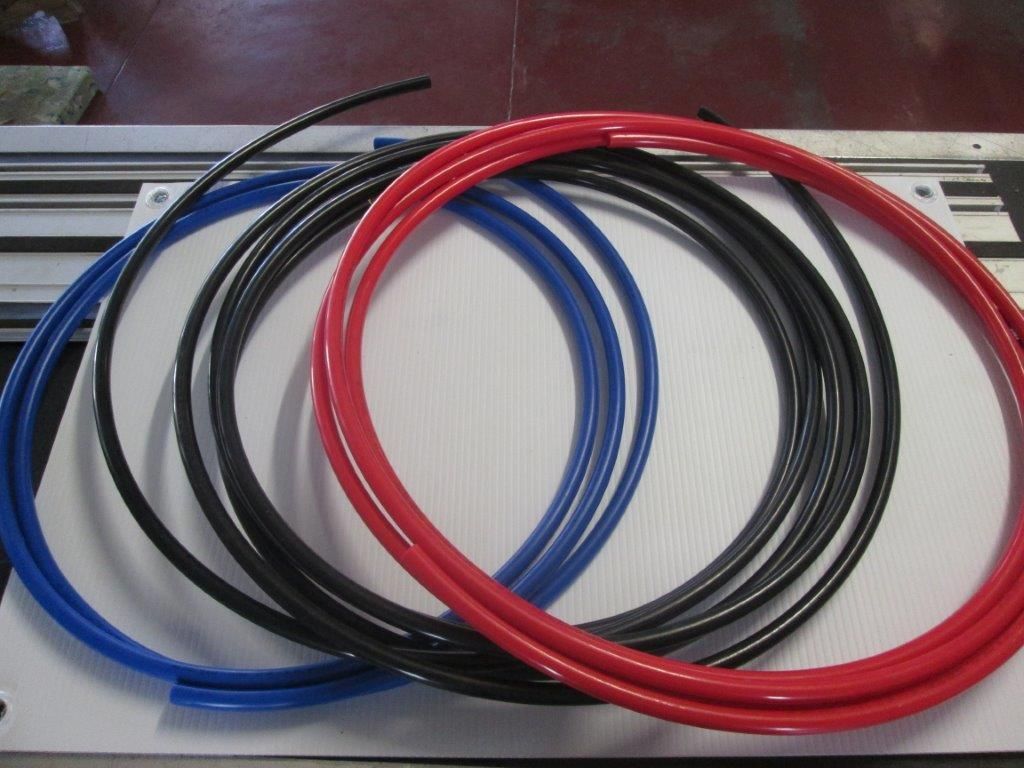 Coiled Blue, Black, And Red Plastic Tubing On A White Surface — Caravan Experts In The Charters Towers Region, QLD
