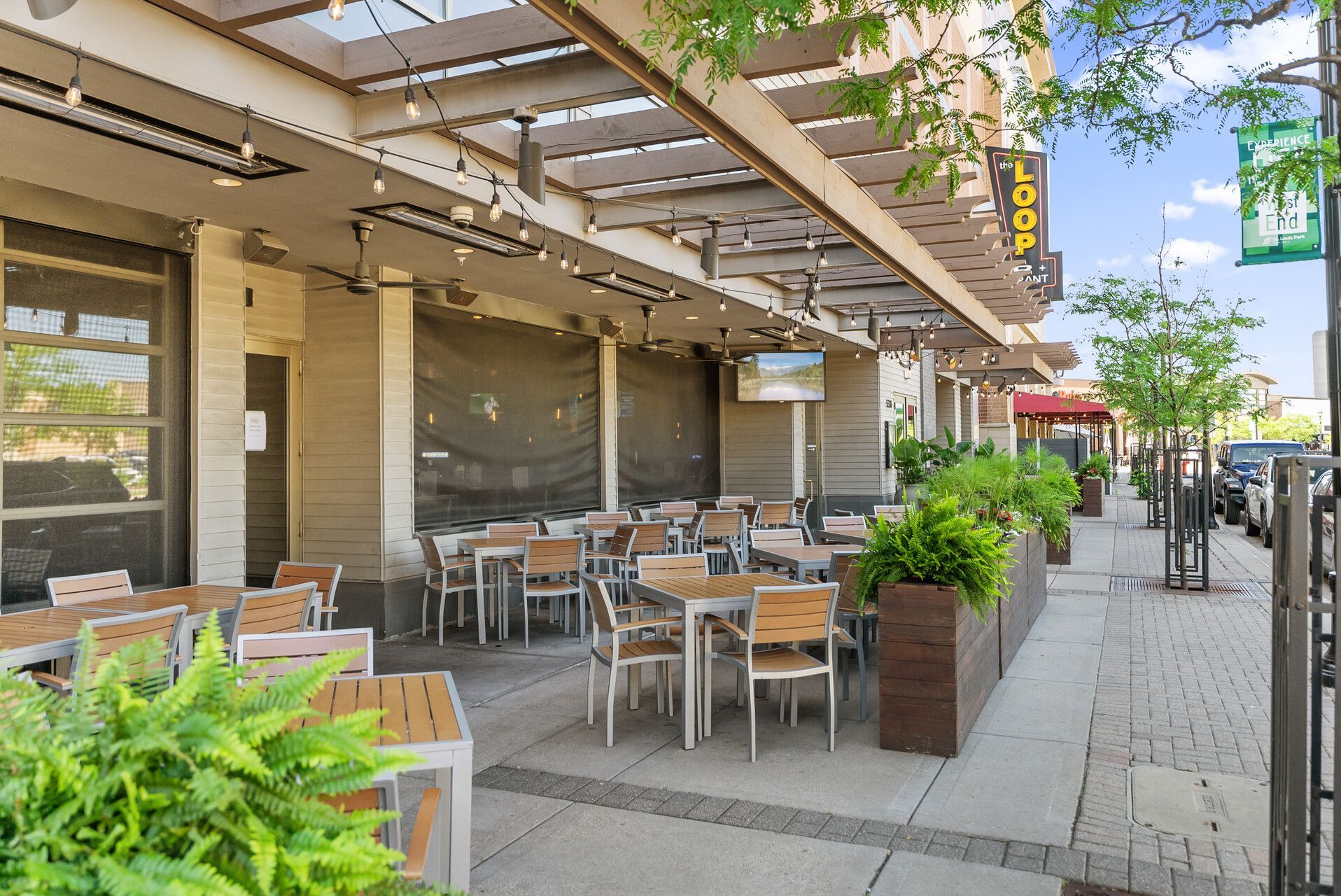 a group of people are sitting at tables on a sidewalk in a city