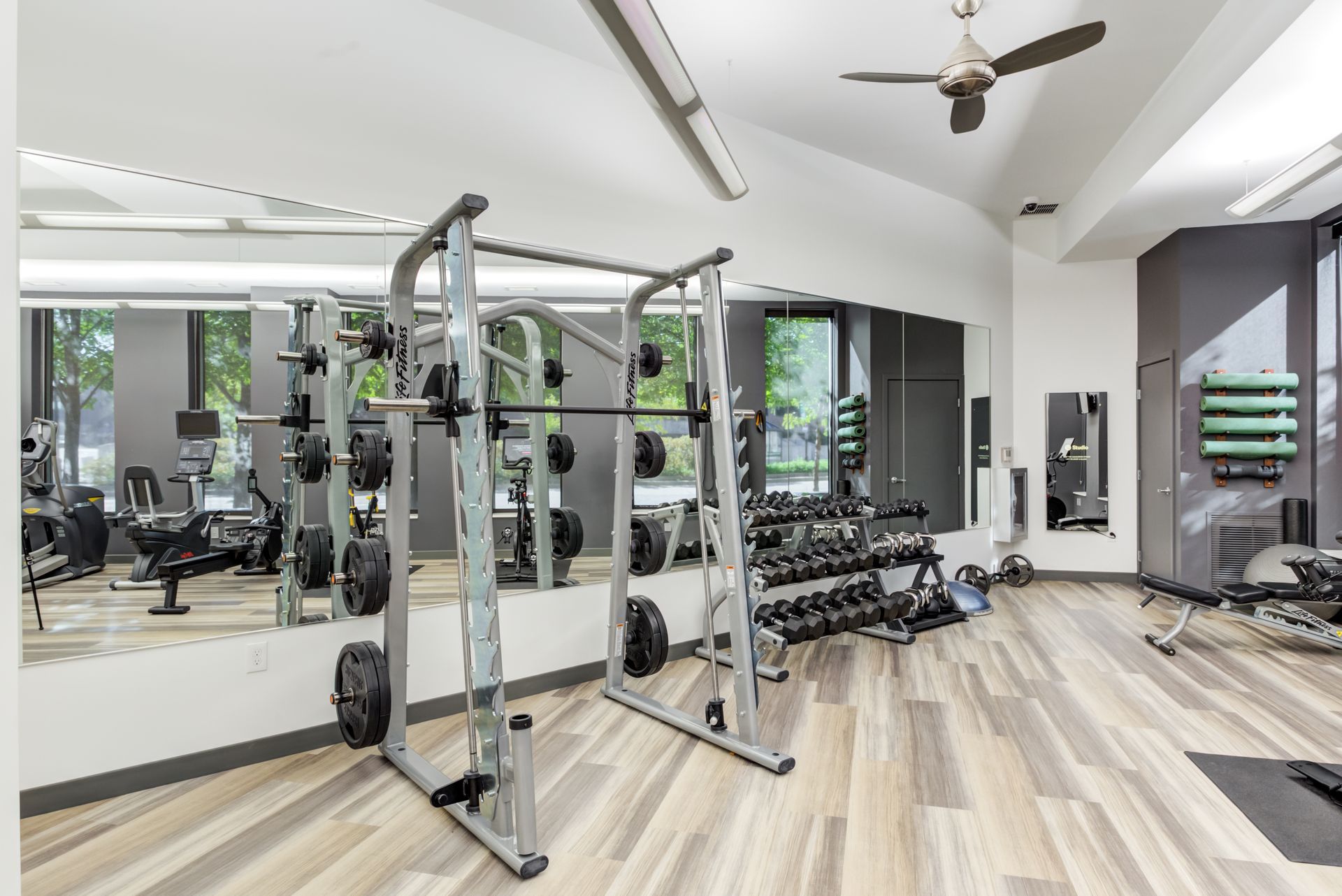 a large gym with a lot of equipment and a ceiling fan .