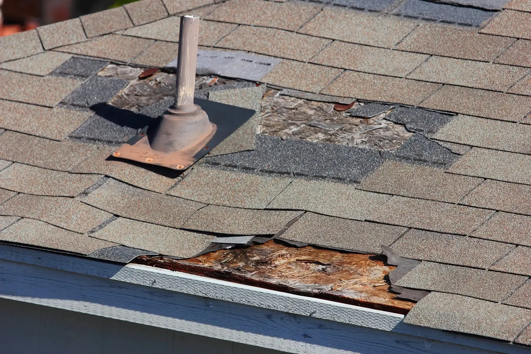 Aerial view of a damaged house with a collapsed roof, broken fence, and debris in the yard.